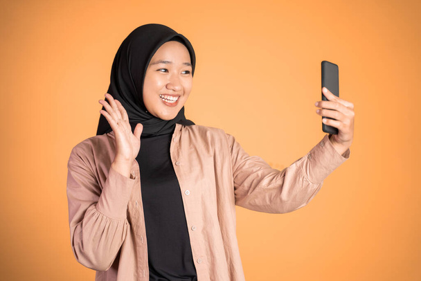 woman in hijab holding a smart phone for selfie - Foto, afbeelding