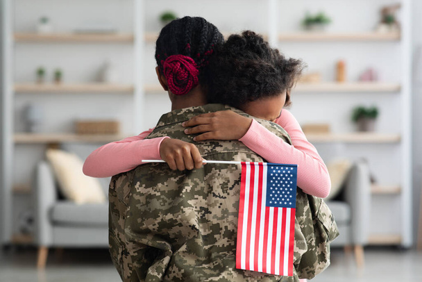 Συναισθηματικό κορίτσι με σημαία των ΗΠΑ αγκαλιάζει τη μαμά της - Φωτογραφία, εικόνα