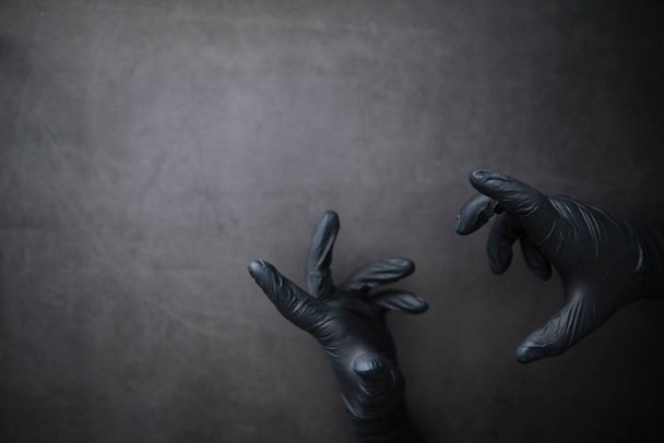 Background of hands in gloves. Black gloves. Hand gestures black gloves. - Foto, afbeelding