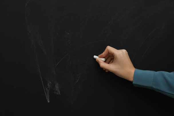 Woman with white chalk near blackboard, closeup. Space for text - Zdjęcie, obraz