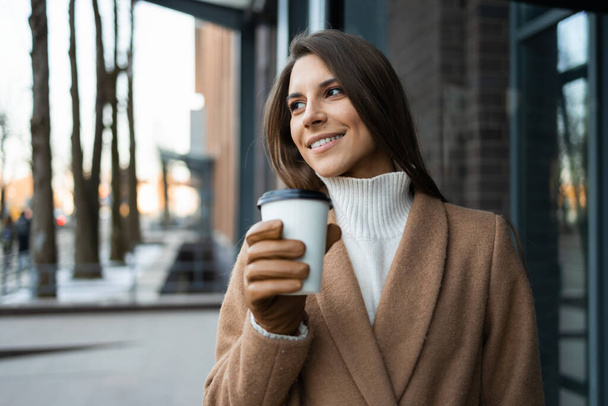 Retrato de uma bela mulher caucasiana com uma xícara de café perto do prédio de escritórios - Foto, Imagem
