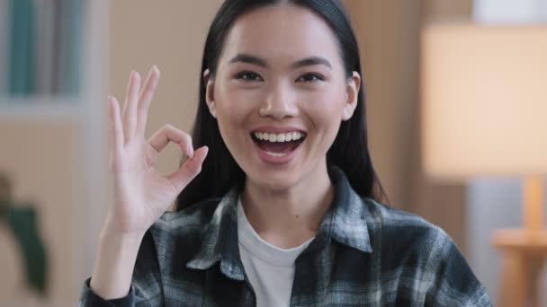Kobieta portret szczęśliwy polecając uśmiechnięty zwycięzca azjatycki kobieta dziewczyna pokazując ok gest wszystko dobrze znak sukces dobra wiadomość zrobić zgoda zwycięstwo symbol składane palce zero patrząc na aparat w domu - Materiał filmowy, wideo