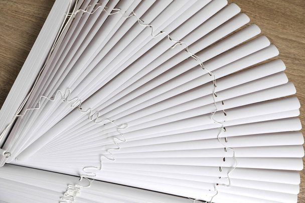 Stylish horizontal window blinds on wooden table, top view - 写真・画像