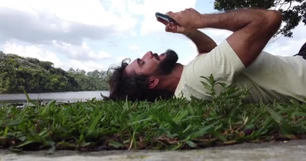Joven hombre de negocios que trabaja al aire libre en un parque verde con su smartphone. Concepto de oficina en casa, móvil. Video de alta calidad - Metraje, vídeo