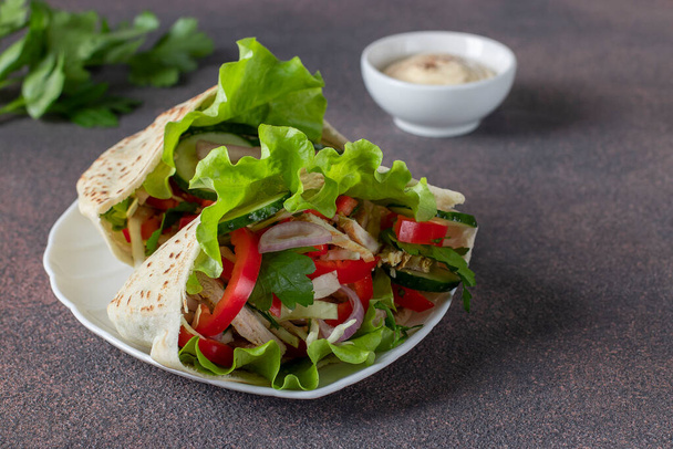 Pita täynnä kanaa, pippuria, kurkkua ja salaattia valkoisella lautasella. Itäinen keittiö - Valokuva, kuva