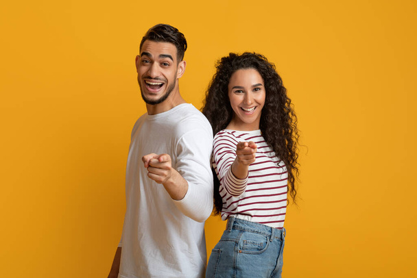 Joyful young arabic couple pointing at camera with fingers - Фото, изображение