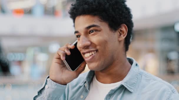 Ritratto felice uomo africano americano condurre una conversazione spensierata su smartphone al chiuso godere di piacevole comunicazione risposta chiamata sorridente ridere condividere notizie per amico di famiglia. Concetto di connessione wifi tecnica - Filmati, video