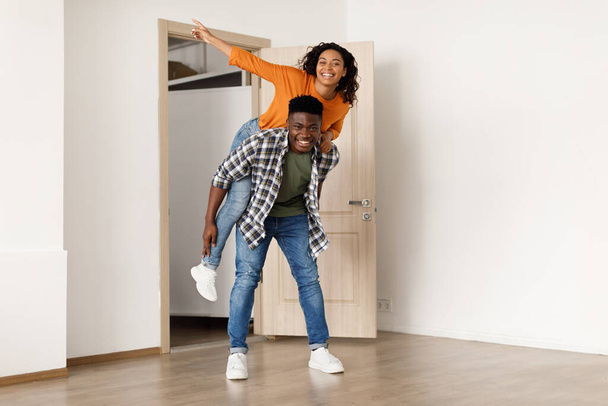 Uomo afroamericano che trasporta donna divertendosi ad entrare in una nuova casa - Foto, immagini