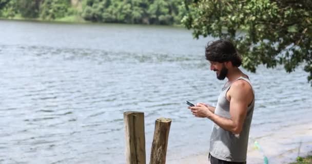 Nuori liikemies työskentelee ulkona vihreässä puistossa älypuhelimellaan. Pääkonttorin konsepti, Mobile. Laadukas video - Materiaali, video