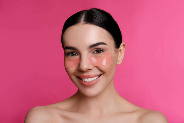 Beautiful young woman with under eye patches on pink background - Foto, immagini
