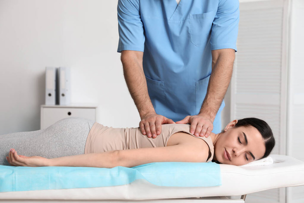 Orthopedist massaging young woman's back in clinic, closeup. Scoliosis treatment - Фото, зображення