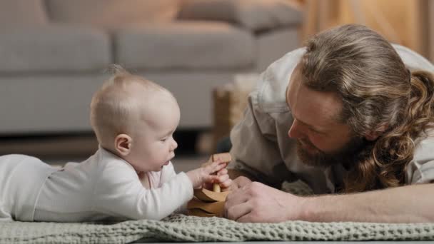 Beyaz aile sakallı baba baba ve küçük kızı bebek yeni doğmuş bebek evde oyuncaklarla oynuyor ahşap inşaatçılar birlikte vakit geçiriyorlar ebeveynlik konsepti oluşturuyorlar. - Video, Çekim
