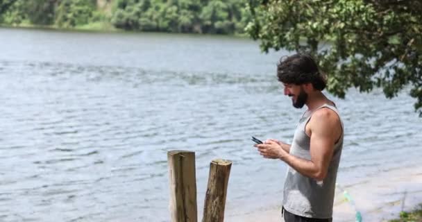 Nuori liikemies työskentelee ulkona vihreässä puistossa älypuhelimellaan. Pääkonttorin konsepti, Mobile. Laadukas video - Materiaali, video