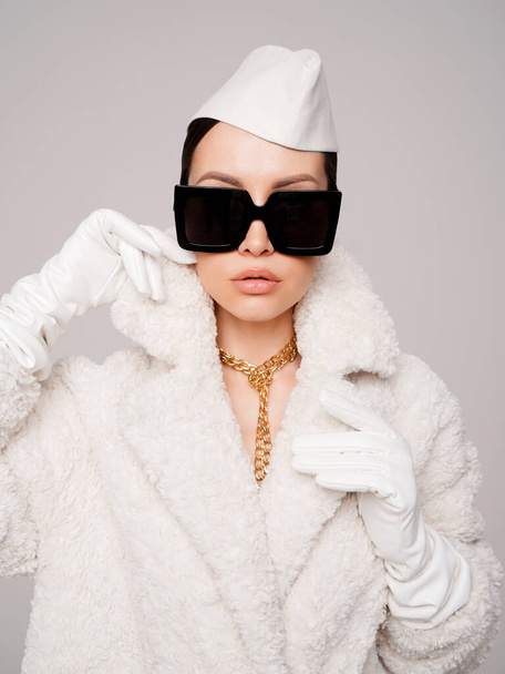 Beautiful young lady in a stylish white outfit. Refined taste. Elegance. Old money style. White faux fur coat - 写真・画像