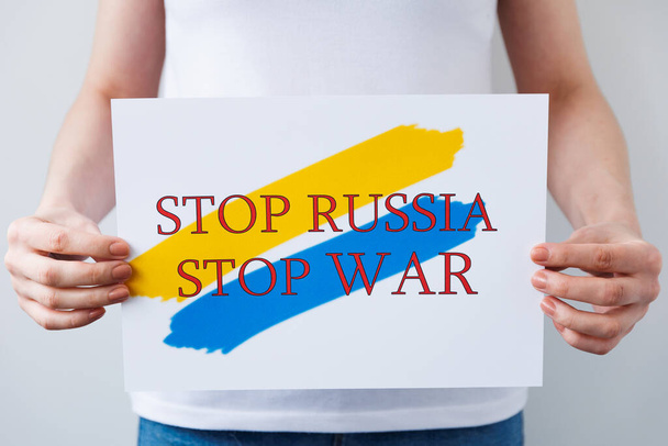 close up of a woman hands is holding a poster with the image of the Ukrainian flag, which says stop war stop russia. - Fotó, kép
