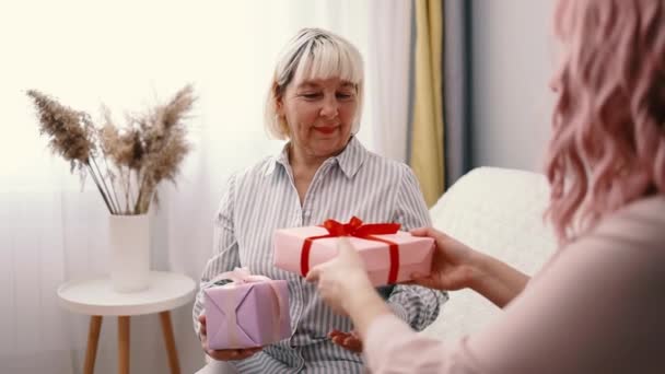 Gift for mother. Happy Caucasian young daughter giving gift box to mother at home - Footage, Video