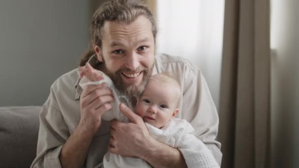 Webcam manzaralı beyaz sakallı baba ve yeni doğmuş bebek küçük kız çocuğu oğul el sallayarak evdeki kamera görüntüleriyle konuşuyor. Çocuk konferansına katılan baba. - Video, Çekim