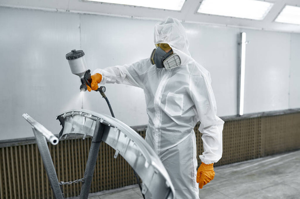 Technician in safety clothing spraying car paint - Foto, afbeelding