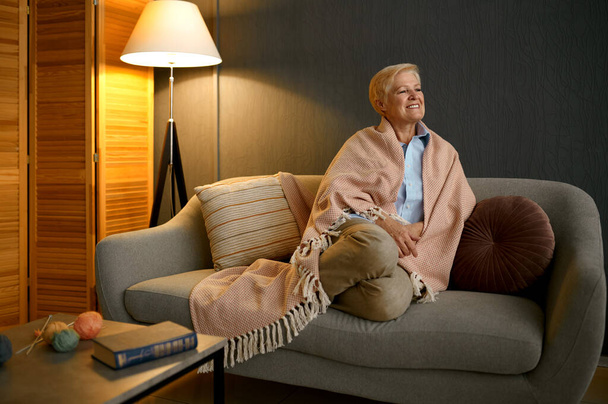 Ικανοποιημένη ηλικιωμένη γυναίκα τυλιγμένη σε κουβέρτα χαλαρώνοντας - Φωτογραφία, εικόνα