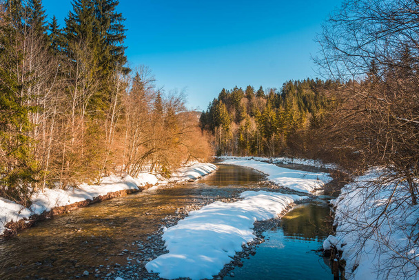 Snowy landscape with a partially frozen creek in the Alps on a sunny winter afternoon - Photo, Image