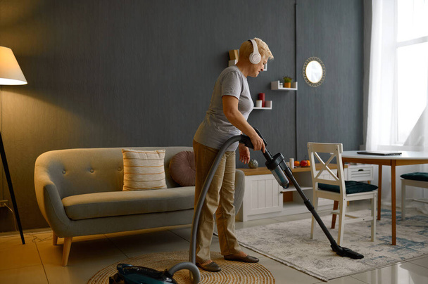 Стара жінка слухає музику прибирання підлоги килим
 - Фото, зображення