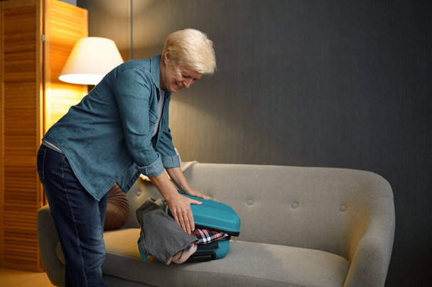 Senior woman packing luggage for new journey - 写真・画像