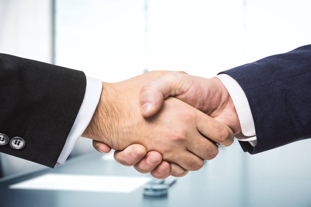 Handshake of two businessmen on the background of bright conference room, partnership concept, close up - Foto, afbeelding