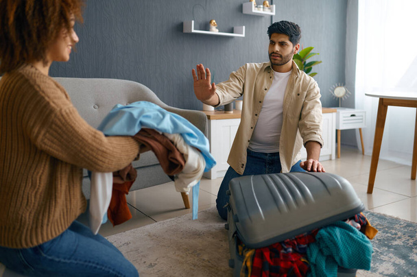 Multiracial couple packing clothes into travel suitcase - Valokuva, kuva