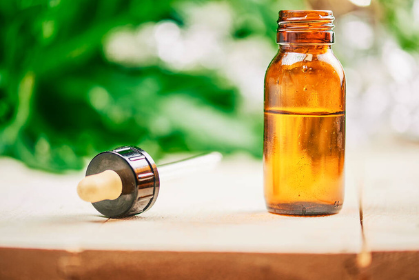 CBD hemp oil, droplet dosing a biological and ecological hemp plant herbal pharmaceutical cbd oil from a jar. - Photo, Image