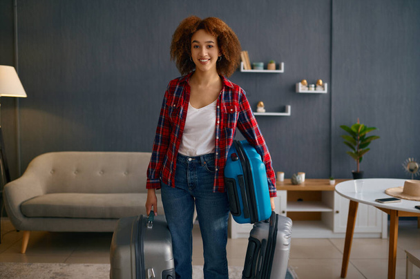 Smiling woman holding baggage in living room - Fotó, kép