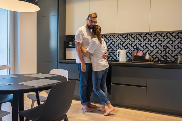 Fiatal pár ölelkezik otthon a konyhában kapcsolat házasság élet együtt - Fotó, kép