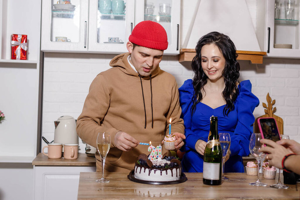 a young man and a girl with glasses of champagne and dessert with a candle - Фото, изображение