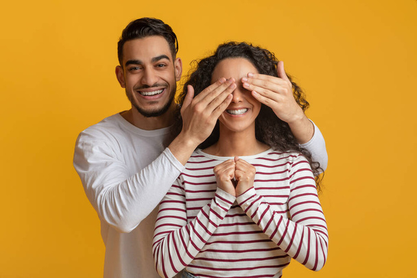 Cheerful Arab Guy Playing Guess Who With His Girlfriend, Covering Her Eyes - Foto, imagen