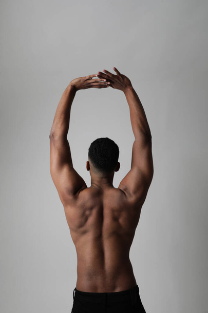 Vertical photo of strong athletic fitness man shows muscular body. Back view.  - Foto, immagini