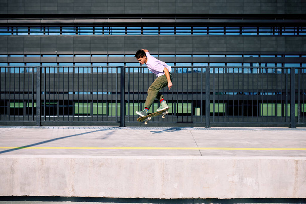 A teenage boy performs tricks on a skateboard. - Photo, image