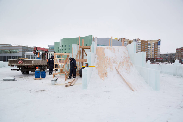 Builders in blue jackets with hoods on the installation of a wooden slide - Photo, Image