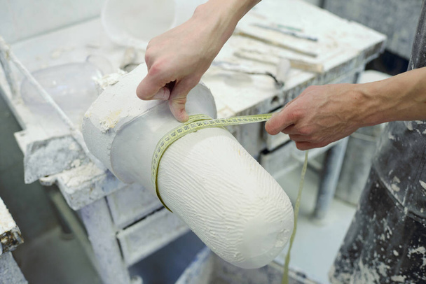 Mains de jeune ouvrier de l'usine de prothèses avec ruban à mesurer - Photo, image