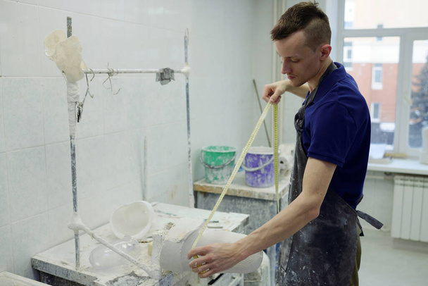 Jonge mannelijke werknemer in schort meetgips gegoten voor prothese - Foto, afbeelding