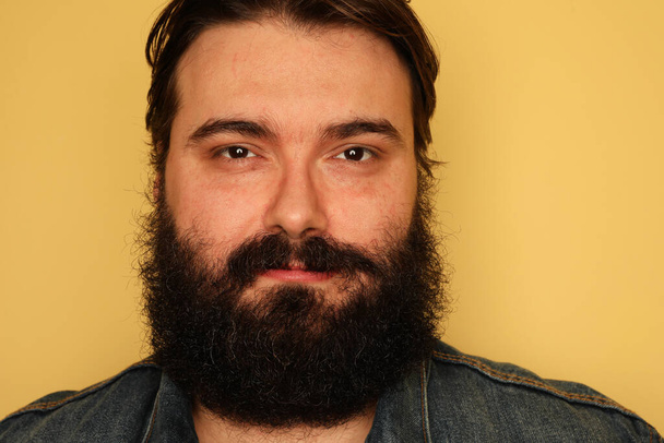 Photo of bearded overweight young man posing on a yellow background.  - Fotografie, Obrázek