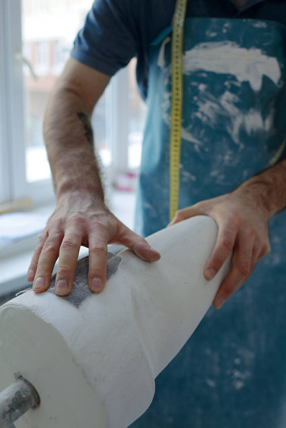 Mão de especialista masculino em gesso de processamento de avental em oficina - Foto, Imagem