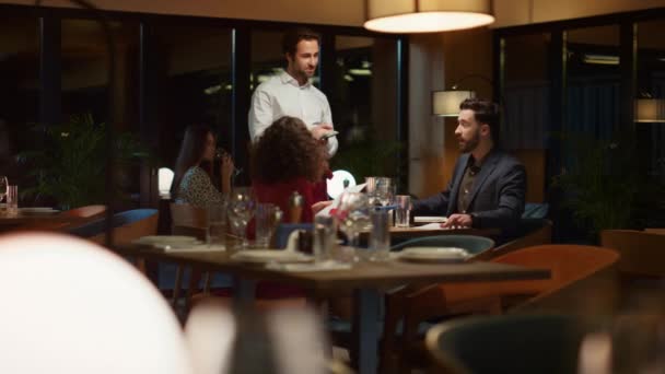 Číšník servíruje multietnický pár na nóbl restauraci večeře rande v noci. - Záběry, video