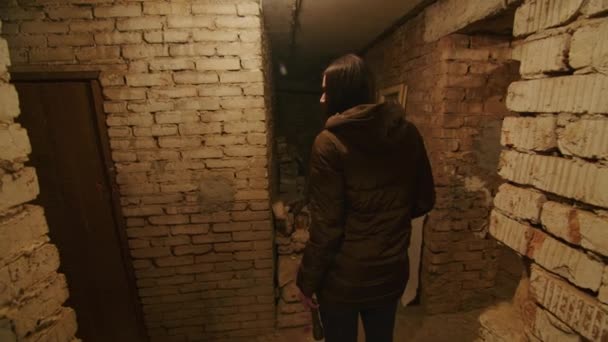ein Mädchen in einem schrecklichen Zustand sucht in einem beängstigenden Keller nach einem möglichen Unterschlupf für den Fall einer Bombenexplosion. Nachrichten über die Spannungen zwischen der Ukraine und Russland. Russische Aggression. Kriegsgefahr. - Filmmaterial, Video