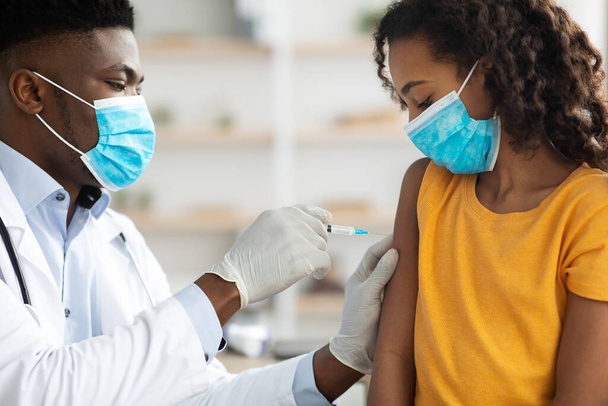 Afroamericano medico making vaccinazione per giovanissima ragazza - Foto, immagini