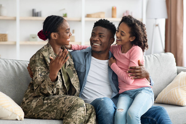 Fröhliche Familie sitzt auf Couch, Soldatenmutter zurück aus dem Dienst - Foto, Bild