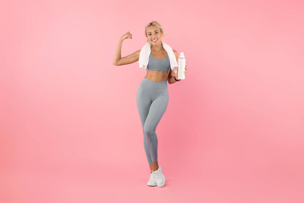 Sporty smiling woman posing at studio with water bottle - Photo, Image