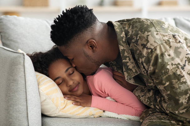 Zwarte man soldaat vertrekt voor militaire dienst, zoenen slapende dochter - Foto, afbeelding