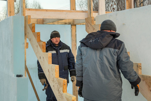 Dos trabajadores montan el marco de la diapositiva de vigas de madera - Foto, imagen