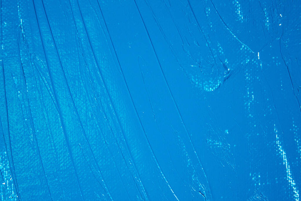 κορεσμένο μπλε αφηρημένο φόντο, εφαρμόζεται τονωτικό αστάρι σε μια λευκή επιφάνεια  - Φωτογραφία, εικόνα