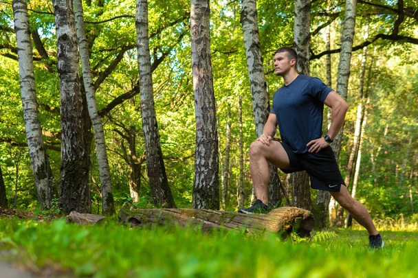 A young enduring athletic athlete is doing stretching in the forest outdoors, around the forest, oak trees.run sport exercise, lifestyle outdoor endurance recreation jog, outside. Autumn energy spring - Valokuva, kuva