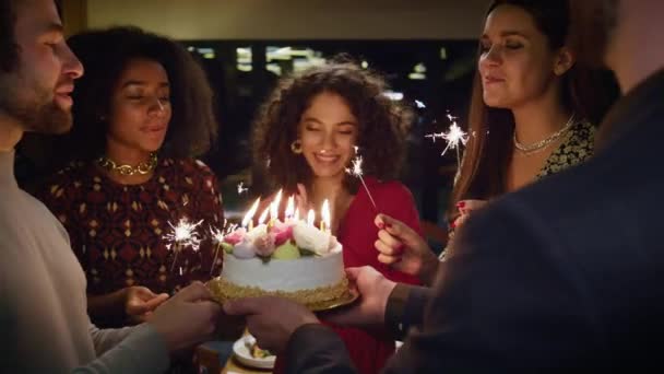 Multietničtí přátelé slaví narozeniny v kavárně. Hořící svíčky v překvapivém dortu - Záběry, video